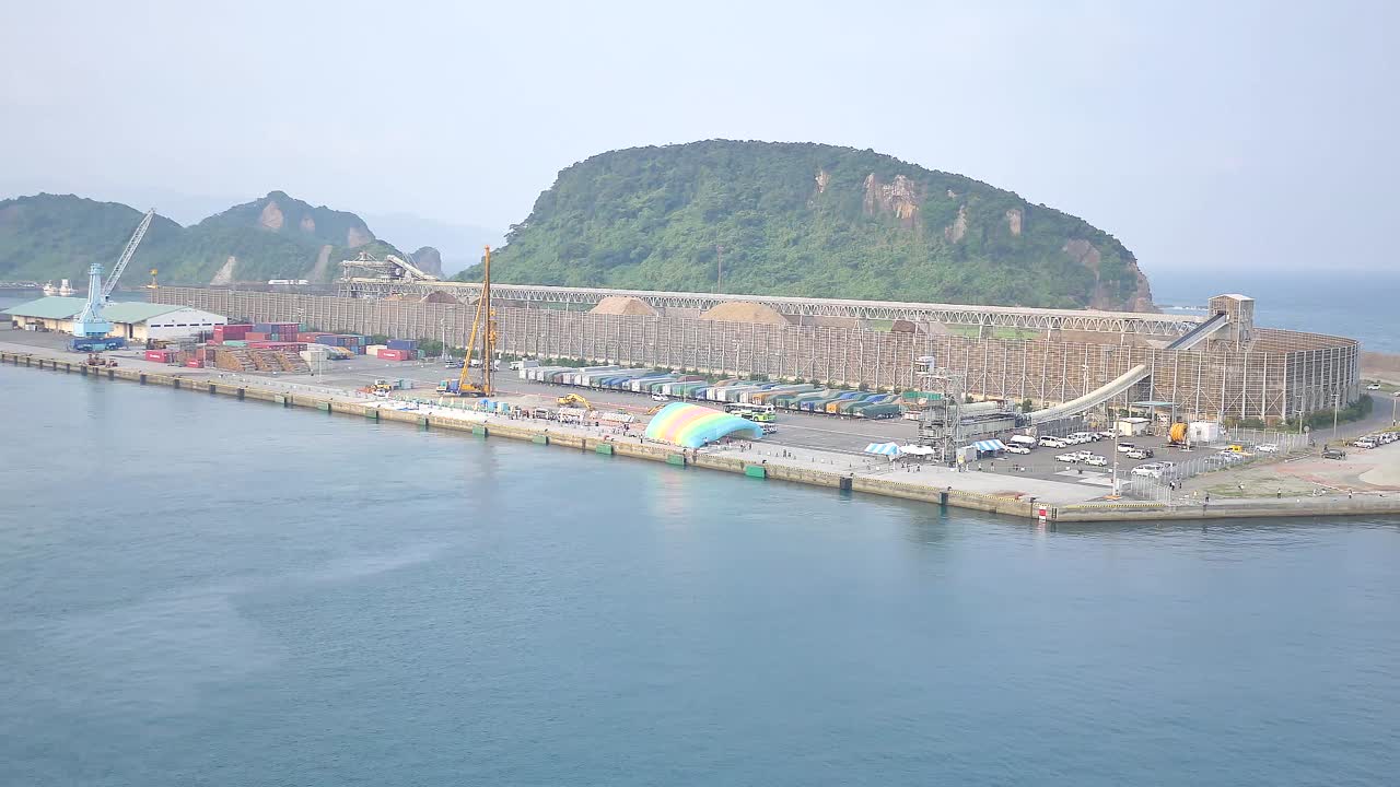 Một tàu du lịch tiến vào Cảng Aburatsu ở Tỉnh Miyazaki, hé lộ vùng nước lặng, những ngọn đồi ven biển và các cơ sở bến cảng