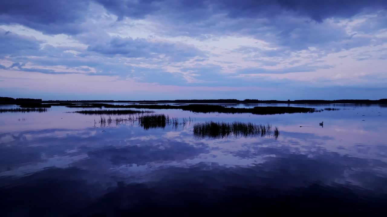Peaceful aerial motion across serene Babīte Lake with clouds mirrored below