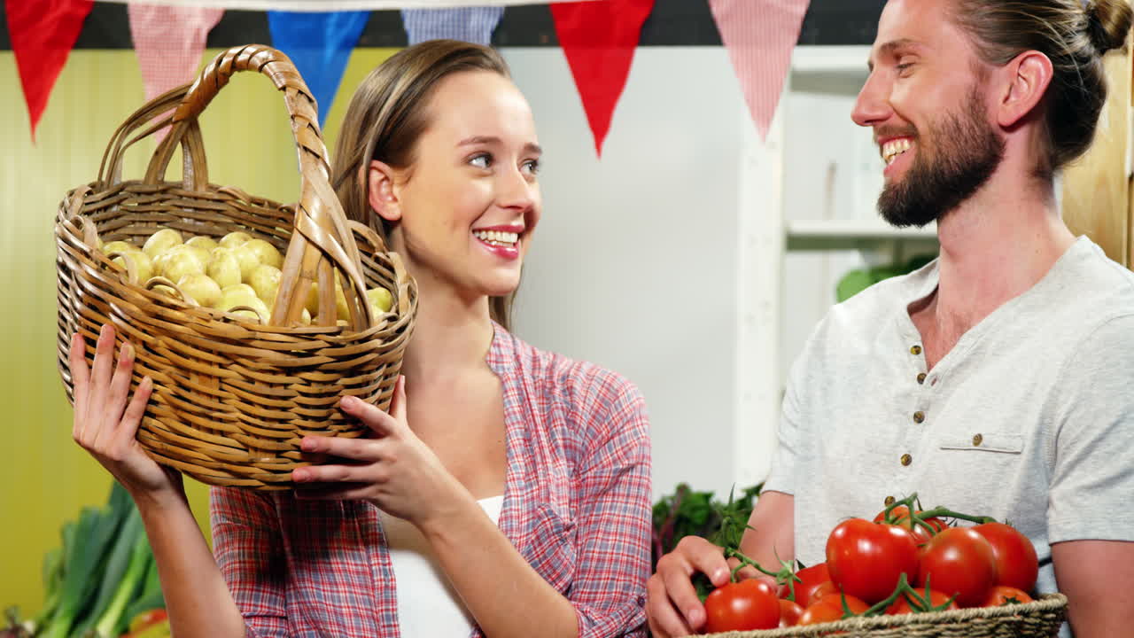 커플 이 바구니 에 채소 를 들고 대화 하고 있다