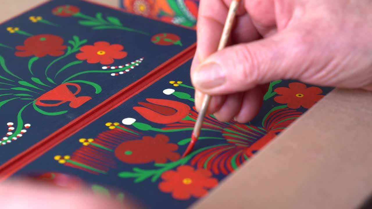 Close-up of hand painting vibrant floral pattern on Matyó decorative panel