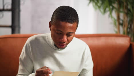 Black-guy-looks-at-family-old-picture-closing-face-by-hand