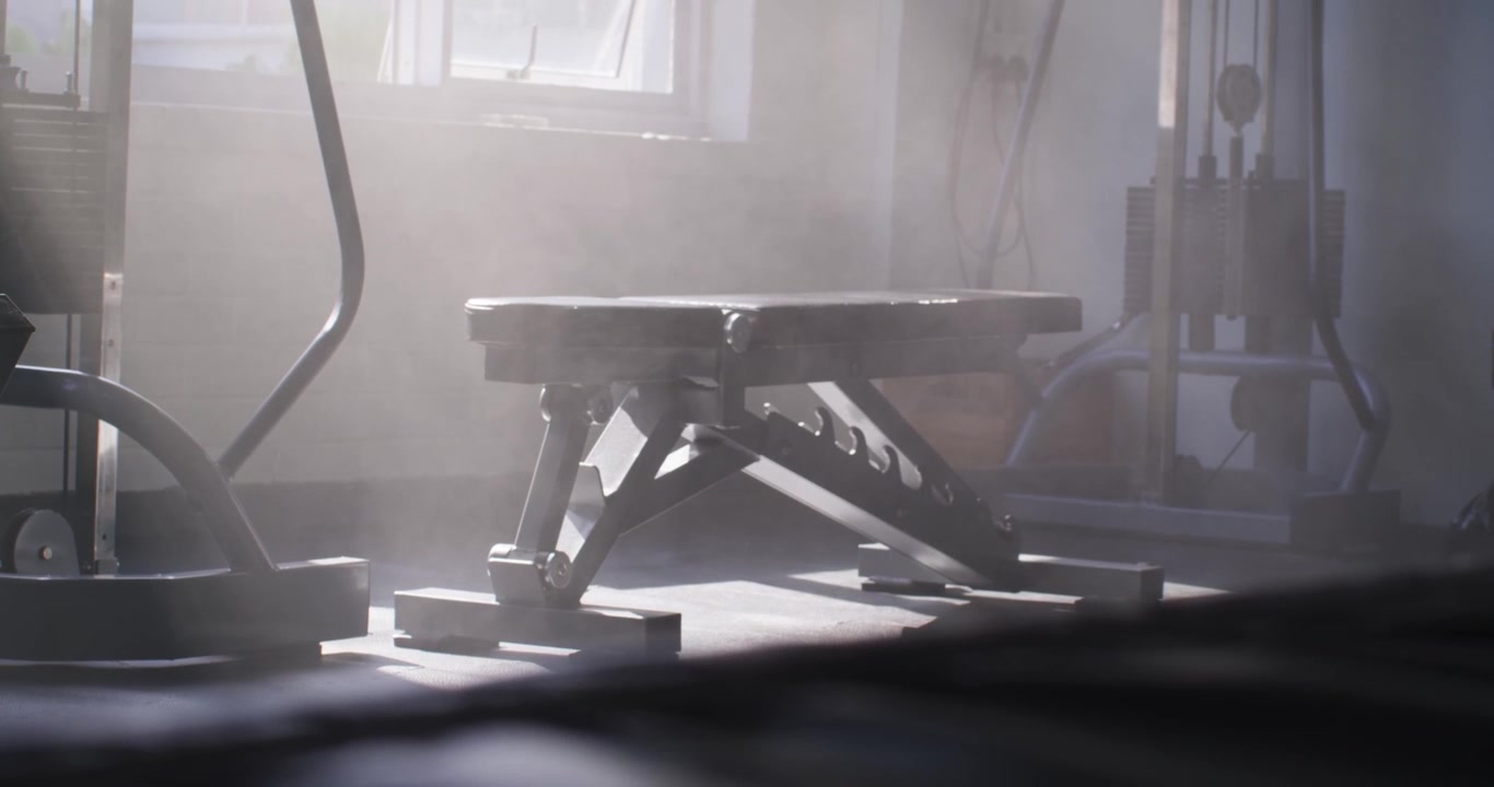 Shifting sunlight is moving dust and nudging workout bench forward near window, showing texture