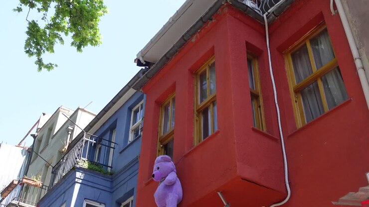 Un edificio rojo con un oso de peluche morado colgando de la ventana