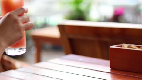 hand stirring a glass of iced drink with straw