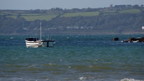 wide-shot-of-small-boat-at-anchor-and-the-sea-crashing-over-rocks