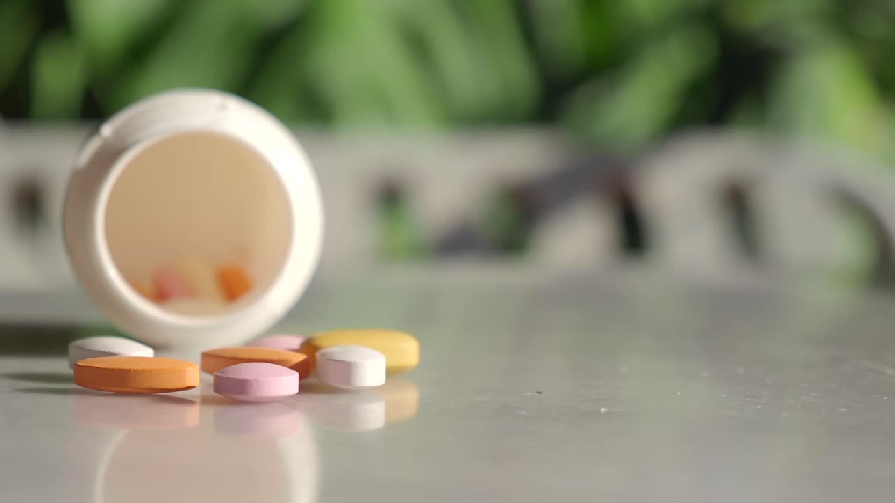 Assorted pills spilling from a white bottle