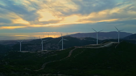 aerial view of a wind farm with rotating electric wind turbines that provide sustainable electricity for renewable energy for optimal environmental protection at golden hour