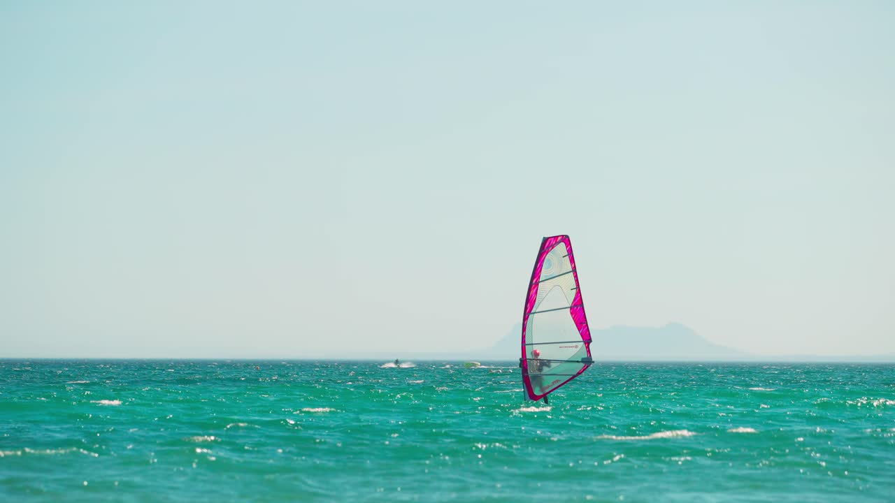 windsurfista en cámara lenta en la costa de españa, con la roca de gibraltar en el fondo
