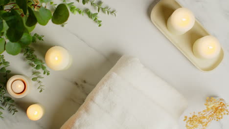 vista aérea mirando hacia abajo en la naturaleza muerta de velas encendidas con hierbas secas planta verde y toallas suaves como parte de la relajante decoración del día de spa