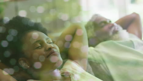 animation of light spots over african american couple relaxing, slow motion