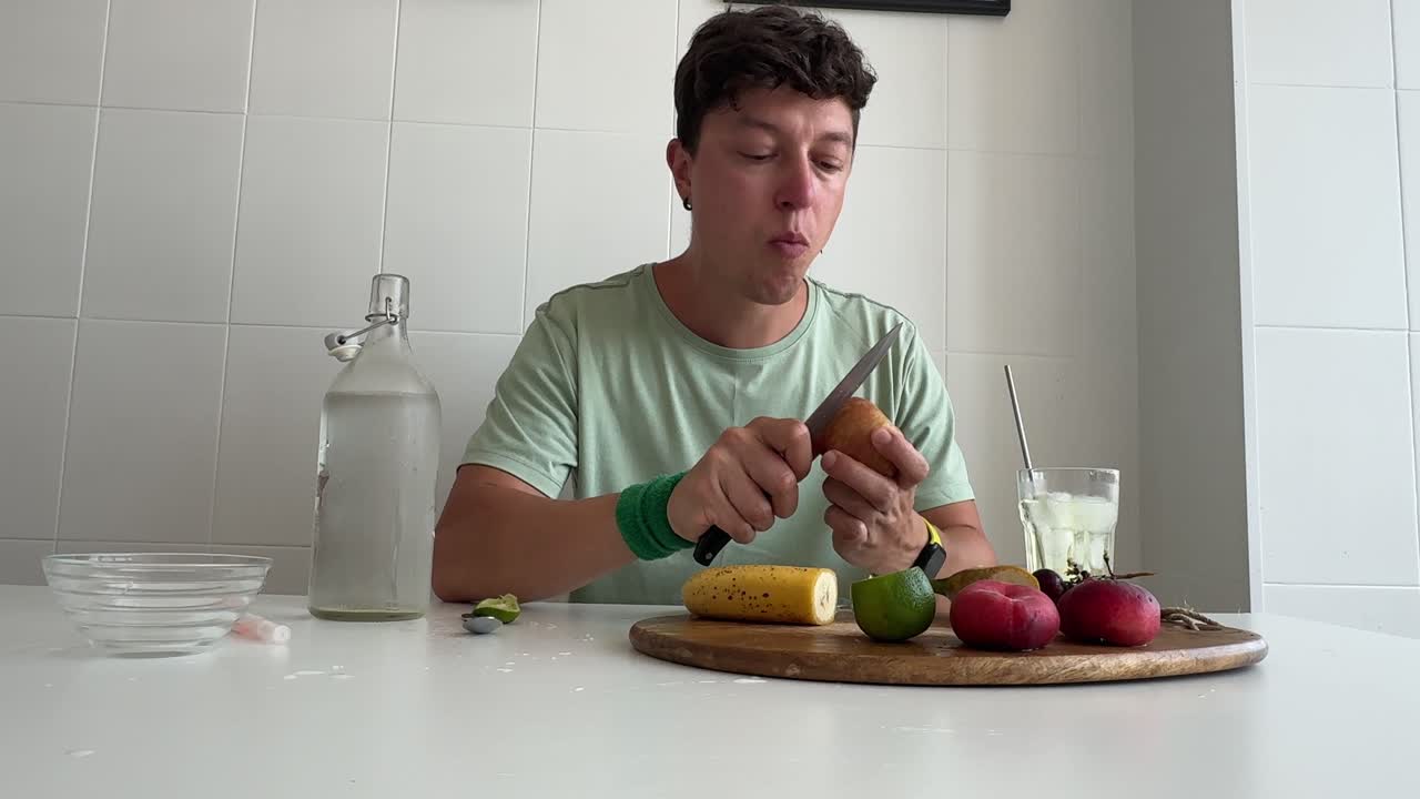 Uomo che mangia frutta fresca e beve acqua in cucina