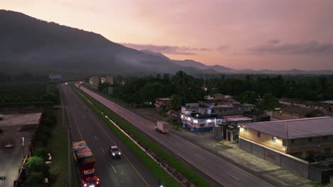 autopista de paso elevado de drones con tráfico en villa altagracia durante el amanecer rosa en república dominicana