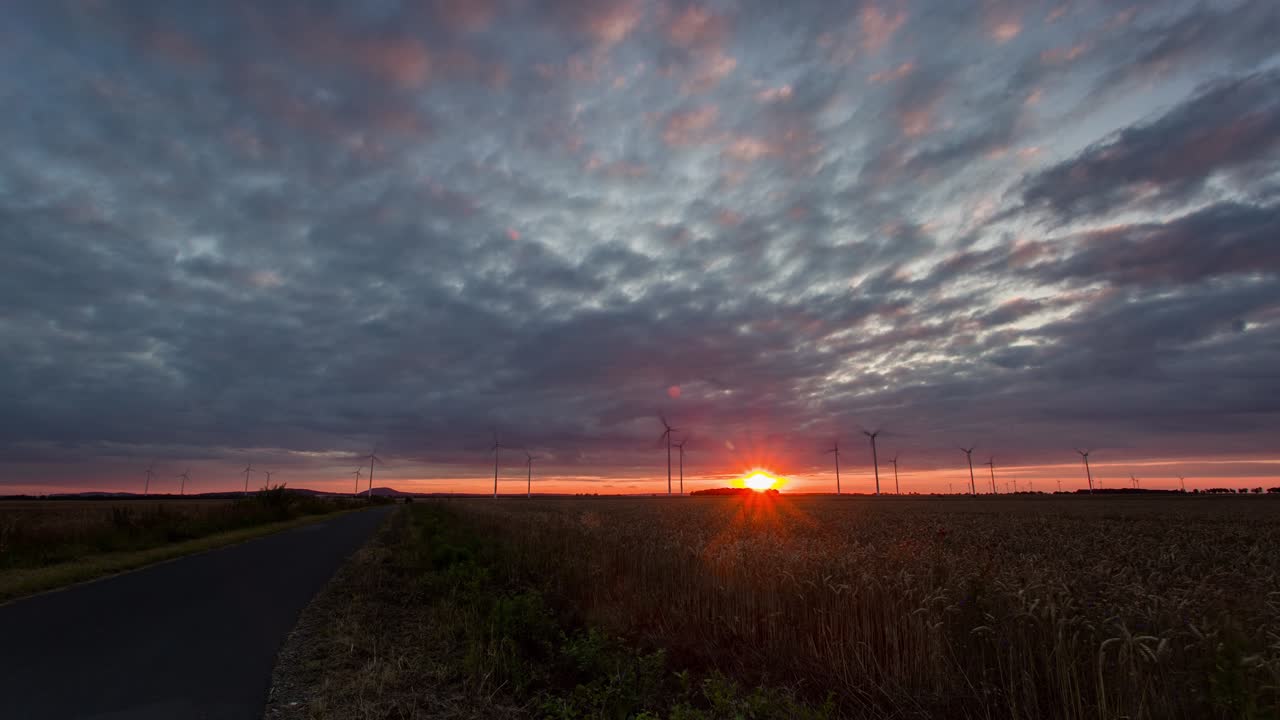 timelapse de una puesta de sol detrás de una granja de molinos de viento