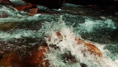 rushing water over big boulders on a cold winter day