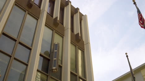 downtown city building with large windows and pan over to american flag in the courtyard