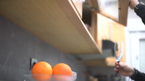 a man opens the kitchen unit to take and put back a stemware