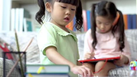 a beautiful asian mother busy working at home while looking after and teaching her children on a laptop computer