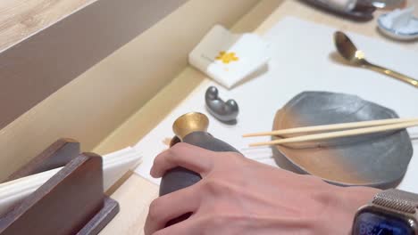 hand pouring sake into a small cup