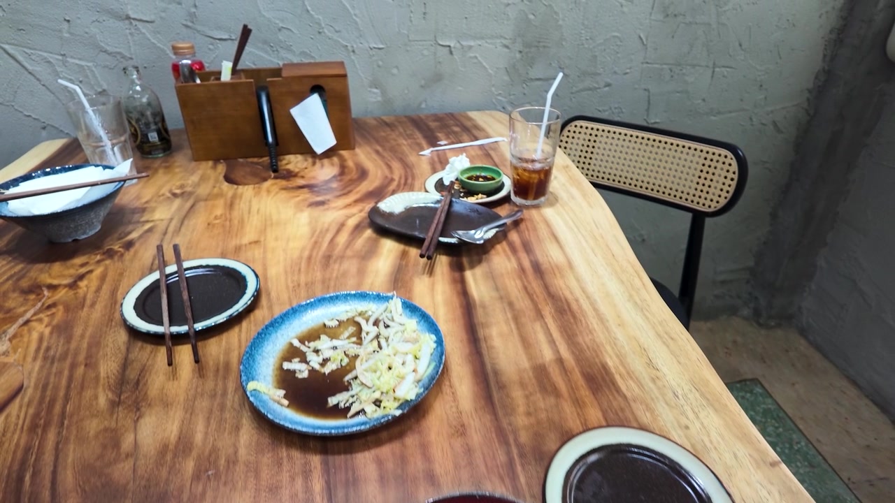 Close-up of a messy restaurant table with empty bowls and chopsticks in Bangkok, Thailand.