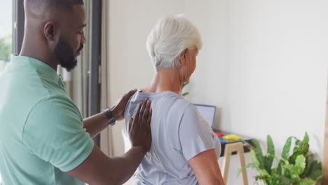 Video-of-african-american-male-physiotherapist-examining-caucasian-senior-woman