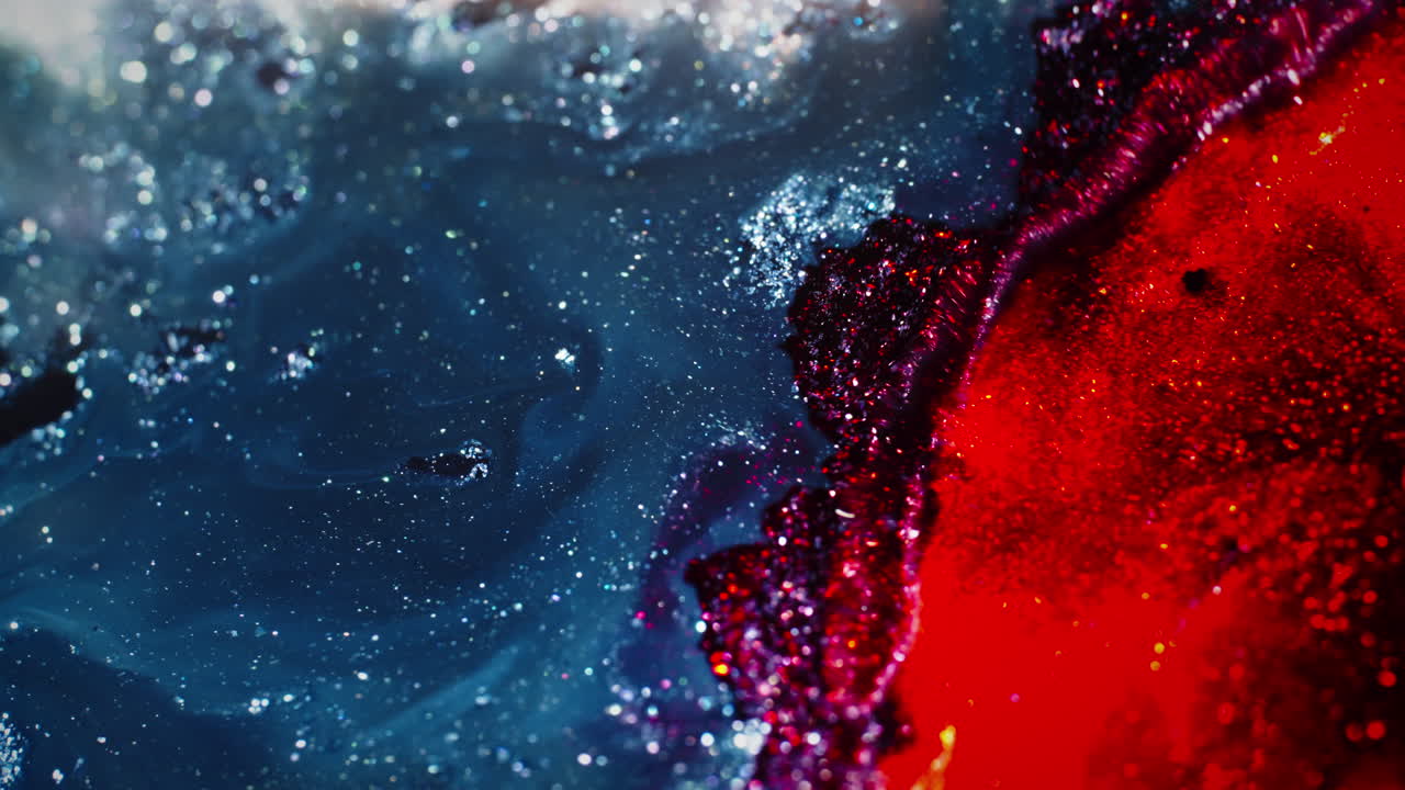 Sparkling blue and white pigments swirl in fluid motion, creating a cosmic, galaxy-like effect
