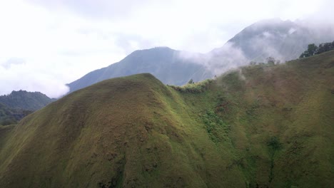 disparo épico de drones que revela la jungla del valle de la selva tropical mientras volaba a través de las nubes en el volcán rijani lombok central, indonesia