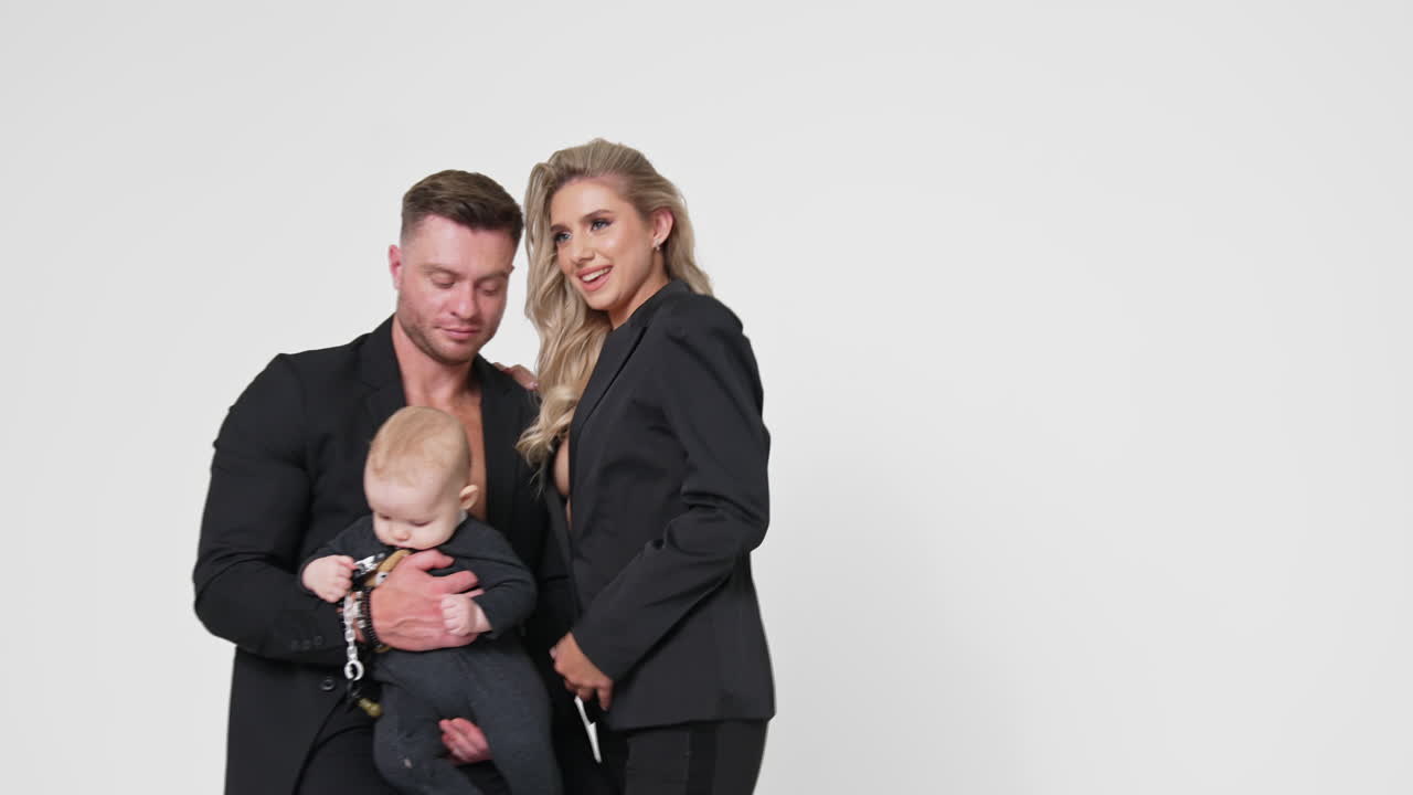 Family image of Caucasian parents with little infant baby. Studio footage of married couple with child. White backdrop.