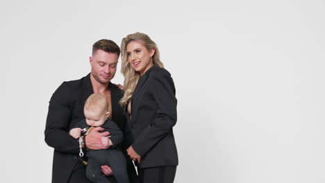 Family image of Caucasian parents with little infant baby. Studio footage of married couple with child. White backdrop.