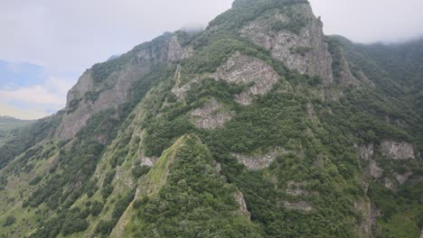 Aerial-shot-of-top-rocky-mountains-in-the-caucasian-region-Georgia-tree-fog-cloud