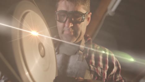 animation of glowing light over caucasian man working in workshop