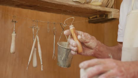 senior caucasian man wearing apron and forming pottery in pottery workshop