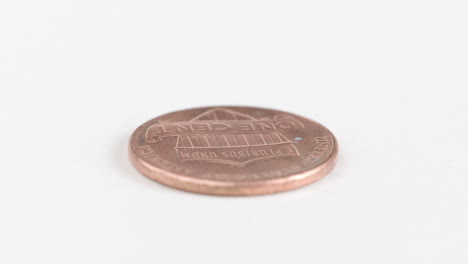 fotografía de cerca de una moneda de un centavo sobre un fondo blanco, girando
