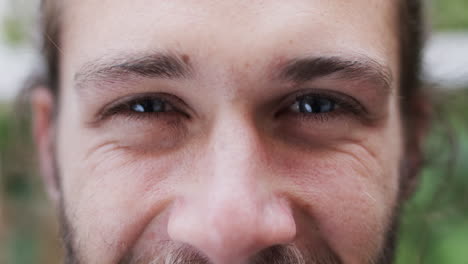 retrato de un hombre caucásico feliz con ojos azules sonriendo en el jardín, cámara lenta