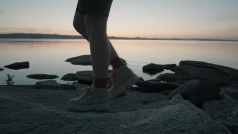 Mujer-Turista-Caminando-En-La-Orilla-Rocosa-Del-Lago-Por-La-Noche