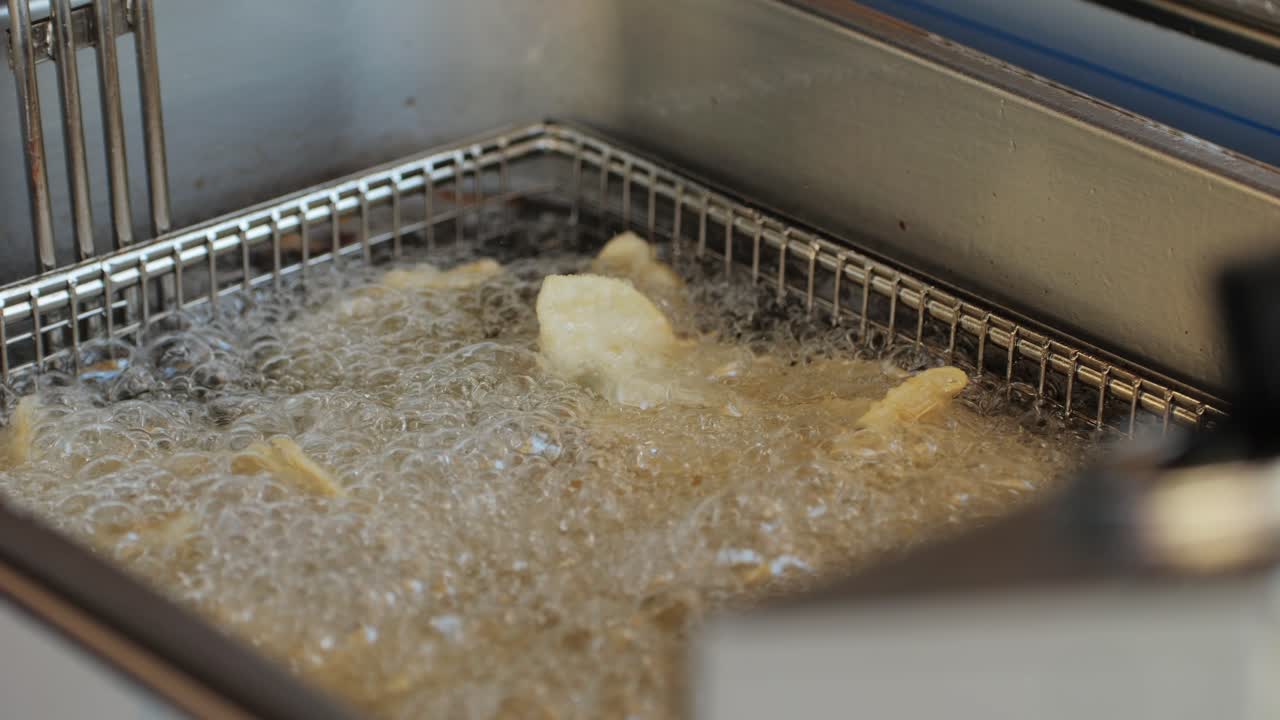 Cooking Chinese and Japanese Jiaozi or gyoza in boiling oil close-up. Dumplings with meat pouring red sweet chilli sauce. Cooking at cafe, restaurant. Asian street food market outdoors