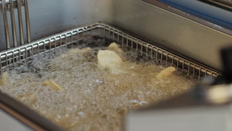 cooking chinese and japanese jiaozi or gyoza in boiling oil close-up. dumplings with meat pouring red sweet chilli sauce. cooking at cafe, restaurant. asian street food market outdoors