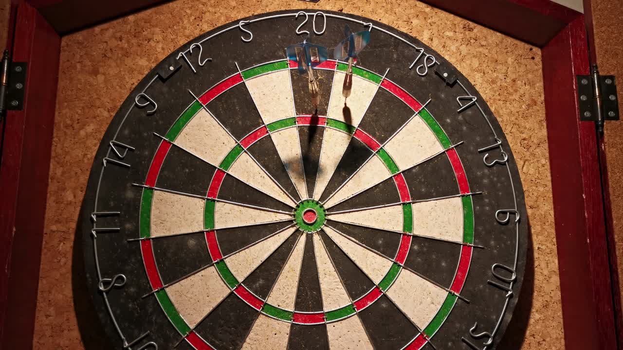 코르크 벽 앞에 걸려 있는 다트 보드의 위쪽 절반을 치는 세 개의 다트