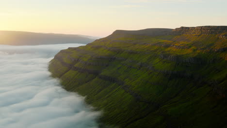 Majestic Green Cliffs Emerging from a Sea of Clouds at Sunrise