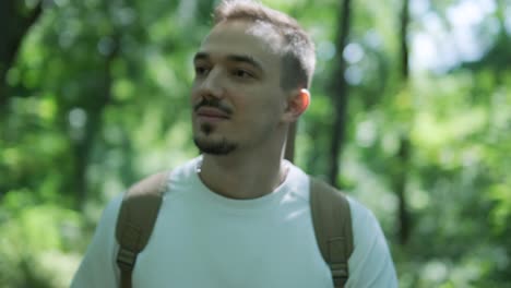 young man walking with guitar on street near forest