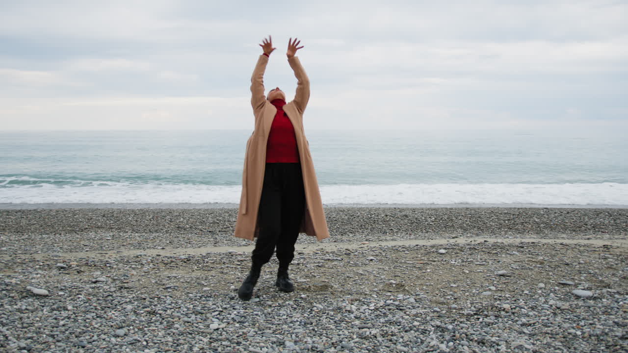 On the Beach A Woman In Brown Coat Dances On A Cold And Cloudy Day