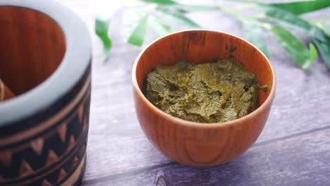 henna paste in wooden bowl with mortar and pestle