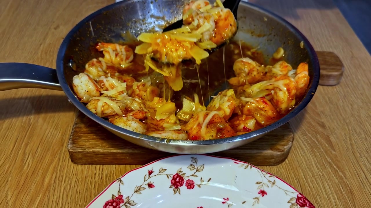 Nærbillede af rejer, der simrer i en rig, krydret tomatbaseret sauce på en pande.