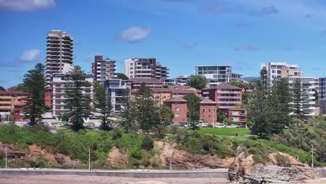 retiro aéreo de los edificios de gran altura de wollongong a las olas que se estrellan en la playa de abajo