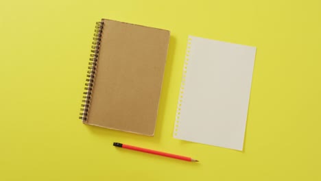 video of notebook, empty sheet with copy space and pencil on yellow background