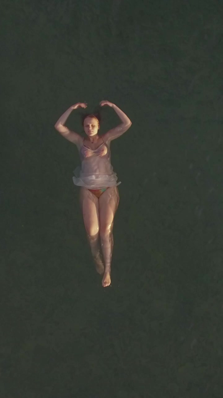 Woman swimming on back in the sea, aerial