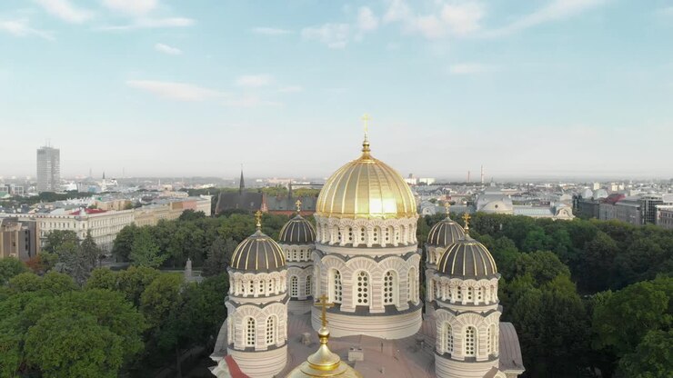 Vista aérea giratória da Catedral da Natividade de Cristo da Letônia no parque Esplanade em um dia ensolarado de verão, com a paisagem urbana de Riga ao fundo.