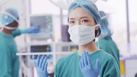 수술실에서 모자, 장갑 및 얼굴 마스크를 입은 아시아 여성 외과의사의 비디오 초상화, 복사 공간