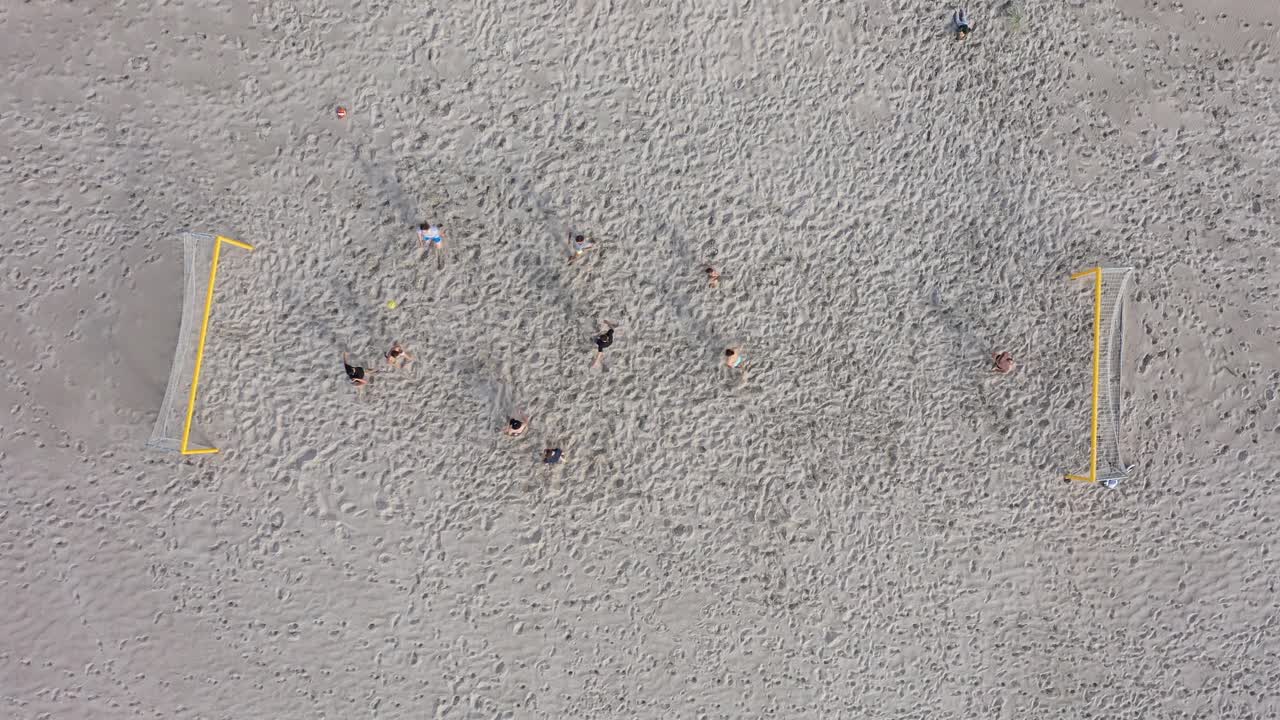 공중:선수들은 하얀 모래 해변에서 지루한 흐린 날에 축구를 합니다.