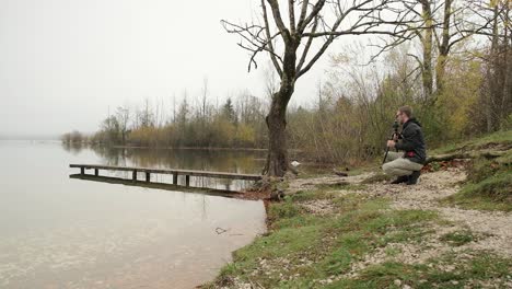 A-photographer-carrying-photography-equipment-to-set-up-to-photograph-next-to-a-lake