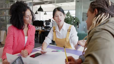 busy diverse designers discussing project at table in office, slow motion